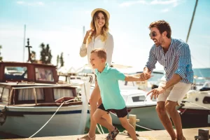 A happy young boy running along a marine dock dragging his parents along as they rush to grab a deal on a new boat