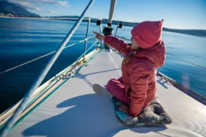 A little girl pointing out across the water wearing her winter clothes enjoying a day on the family yacht