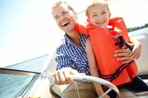Happy man, child and boat on lake for travel, summer journey and holding for safety. Dad, young boy and smile on yacht for water fun.
