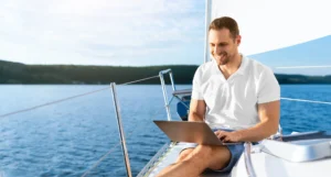 Happy Man On Yacht Sitting With Laptop