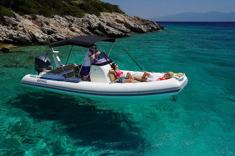 BRIG Eagle 6.7 RIB boat with people enjoying clear blue water near a rocky island