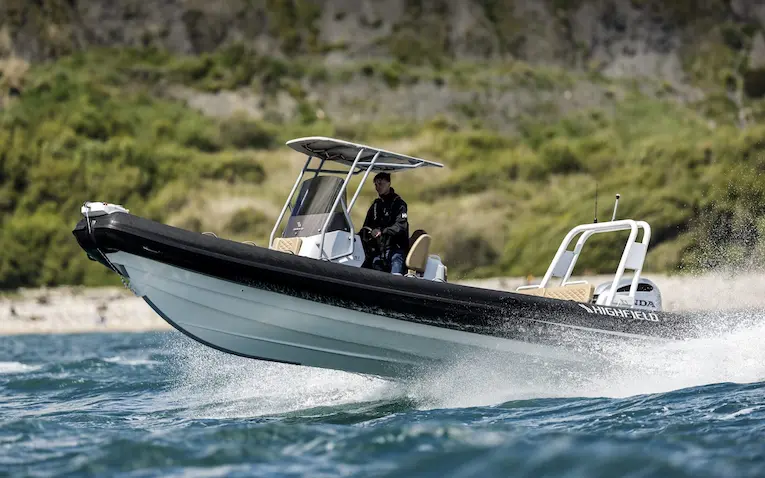 Highfield Sport 760 RIB boat with a single engine speeding on water, showing its deck space and sturdy design.